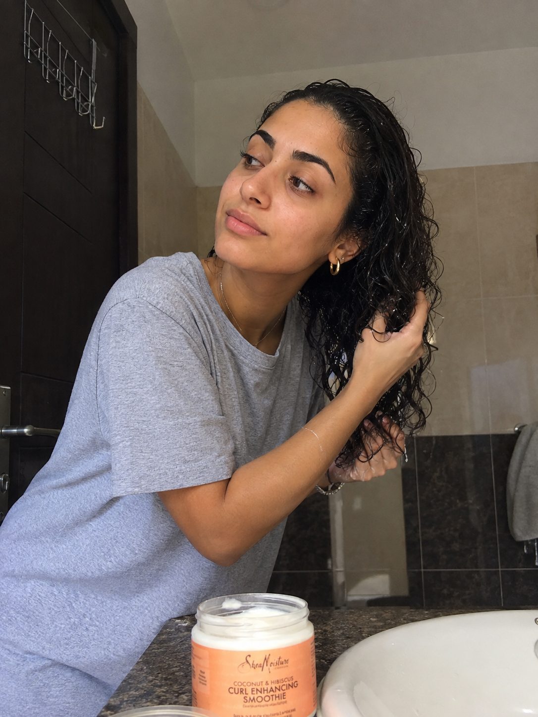 Scrunching curl cream into curly hair before letting it fully air dry