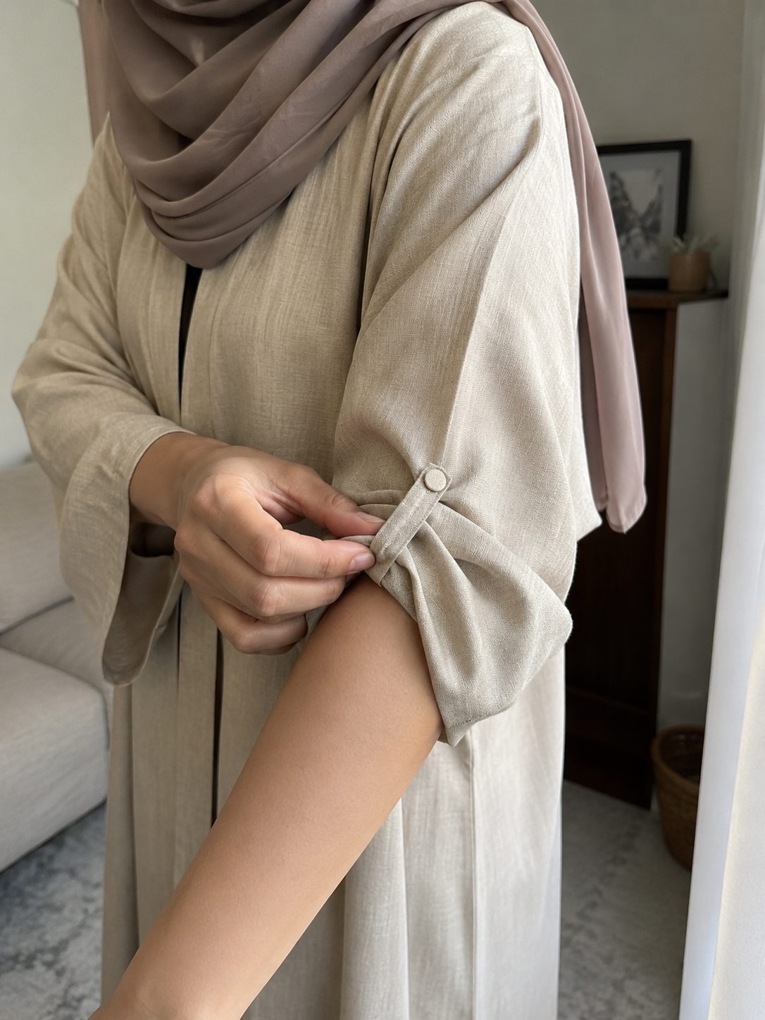 Rolling a wide abaya sleeve and securing it with a button loop